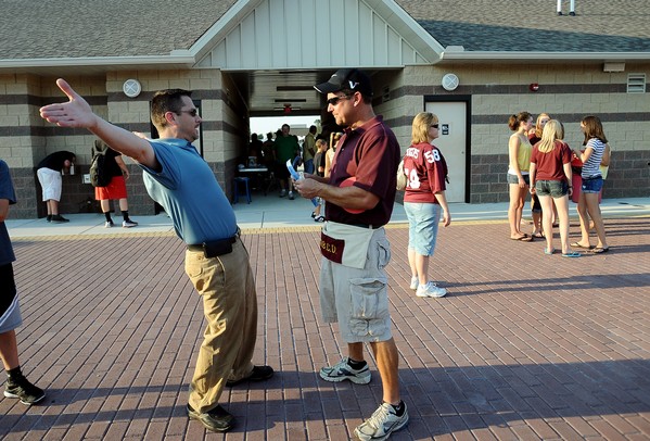 Dexter fan Mark Copland demonstrates the amount of raffle tickets he'd like to volunteer Pat Birmingham as they stand in front of the field house before the start of Friday night's game against Skyline.